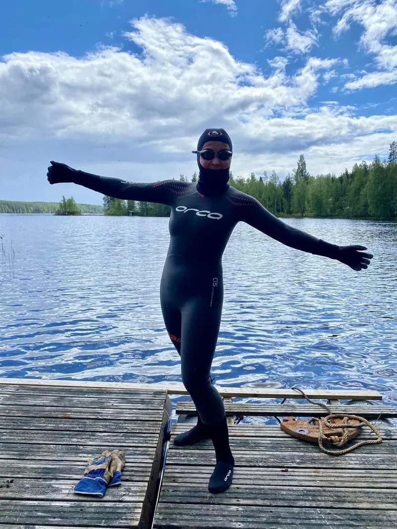 Uimari märkäpuvussa laiturilla järven rannalla