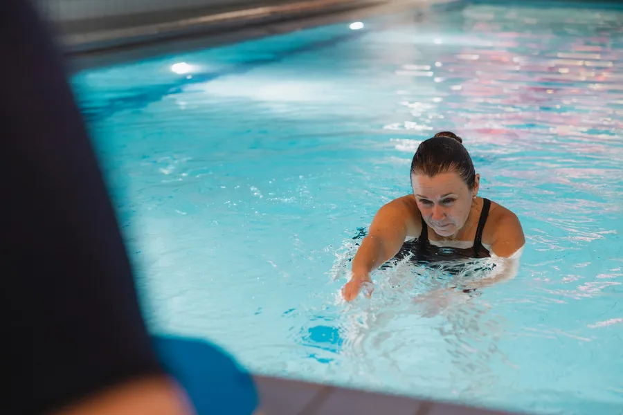 A swimming instructor guiding an adult swimmer in the pool